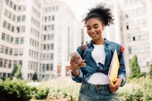 A college graduate smiles at her phone.