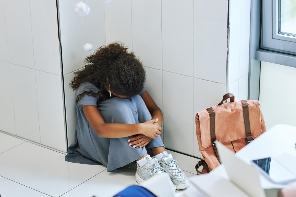 Child sitting with her head to her knees in hallway