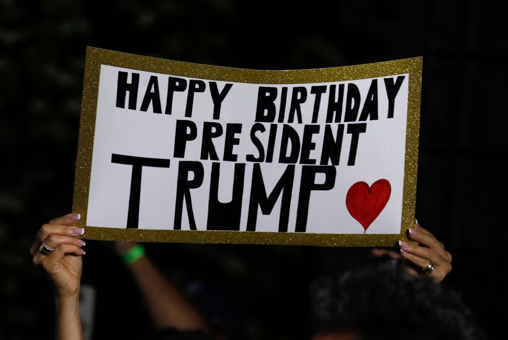 Supporters holds up sign saying "Happy birthday President Trump" with heart sign.