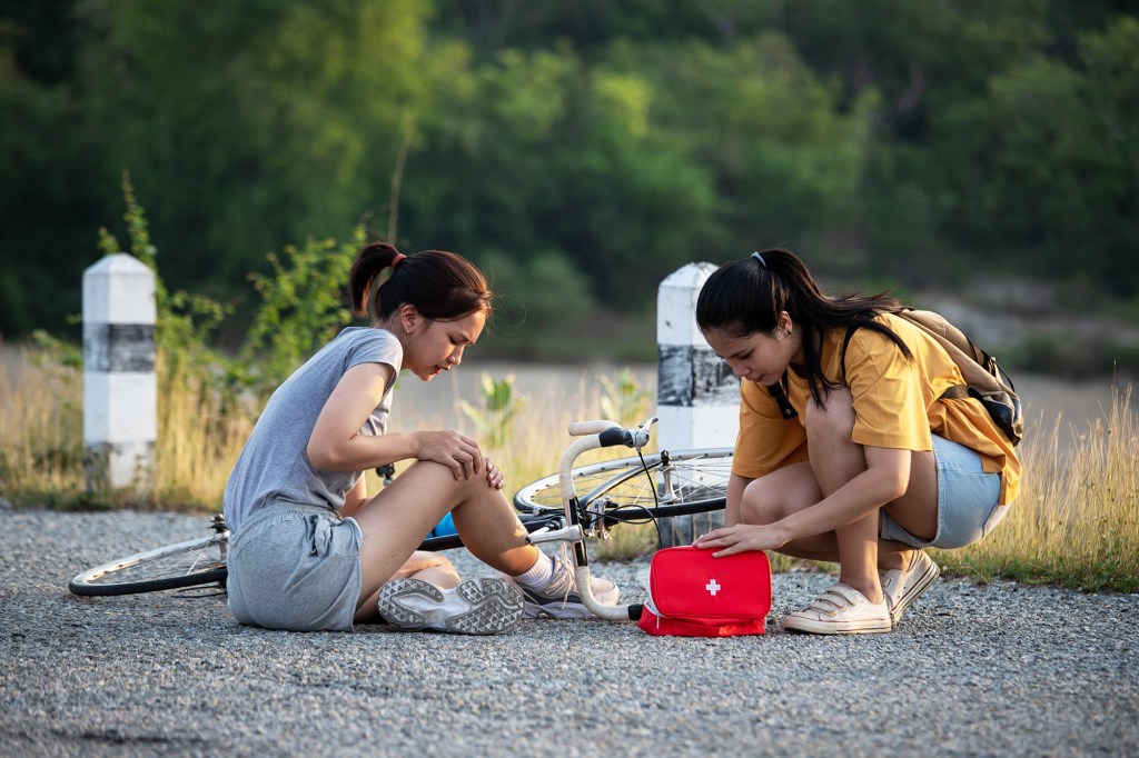 Asian girl having injury while cycling outdoors .