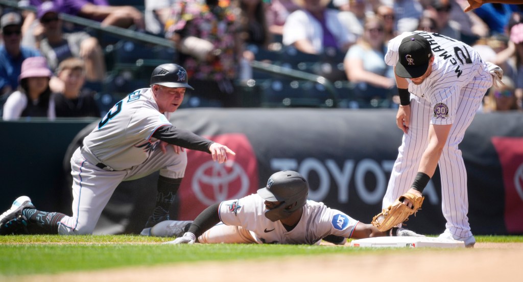 Miami Marlins third base coach Jody Reed, left, directs Jonathan Davis to slide safely into third base for a triple.