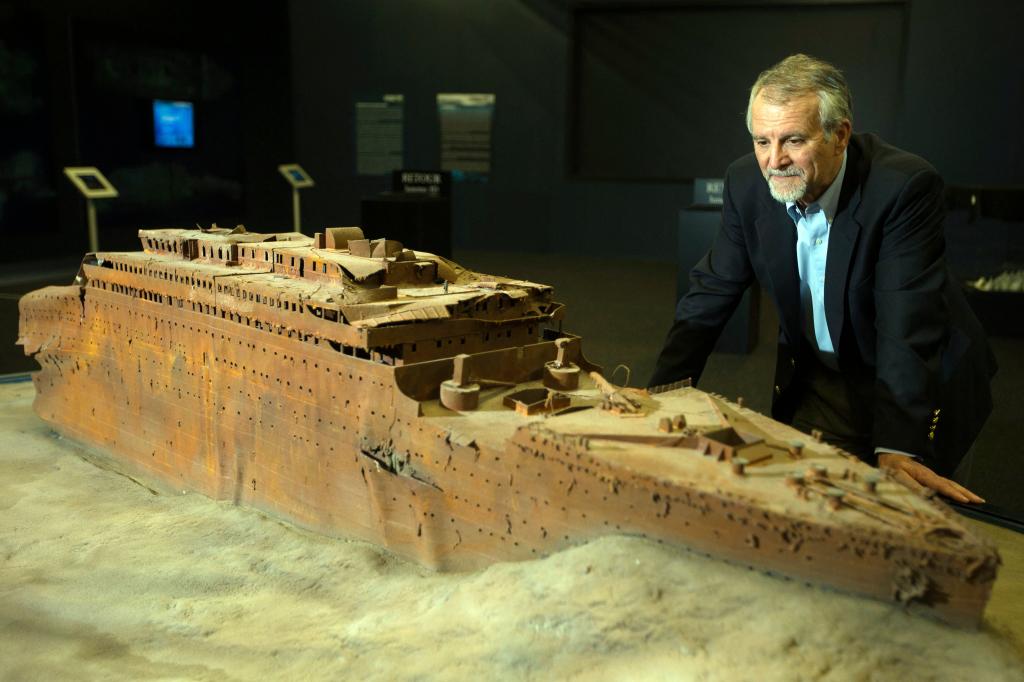 Paul-Henri Nargeolet, director of a deep ocean research project dedicated to the Titanic, poses next to a miniature version of the sunken ship inside a new exhibition.