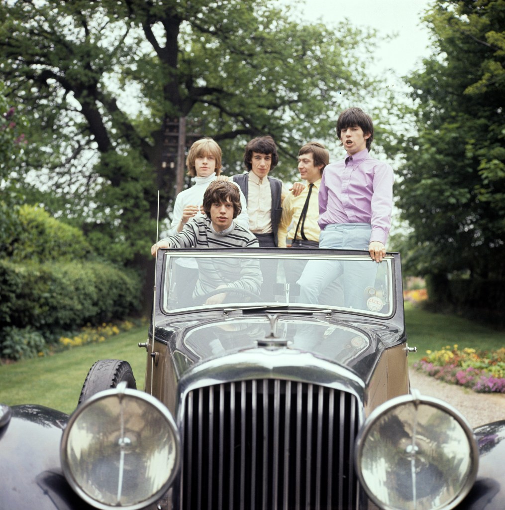 The Rolling Stones — seen here in a vintage car in 1964 — were “not much more than unbrushed Beatles dressed in play-clothes” before they met the women who would shape and influence them. 