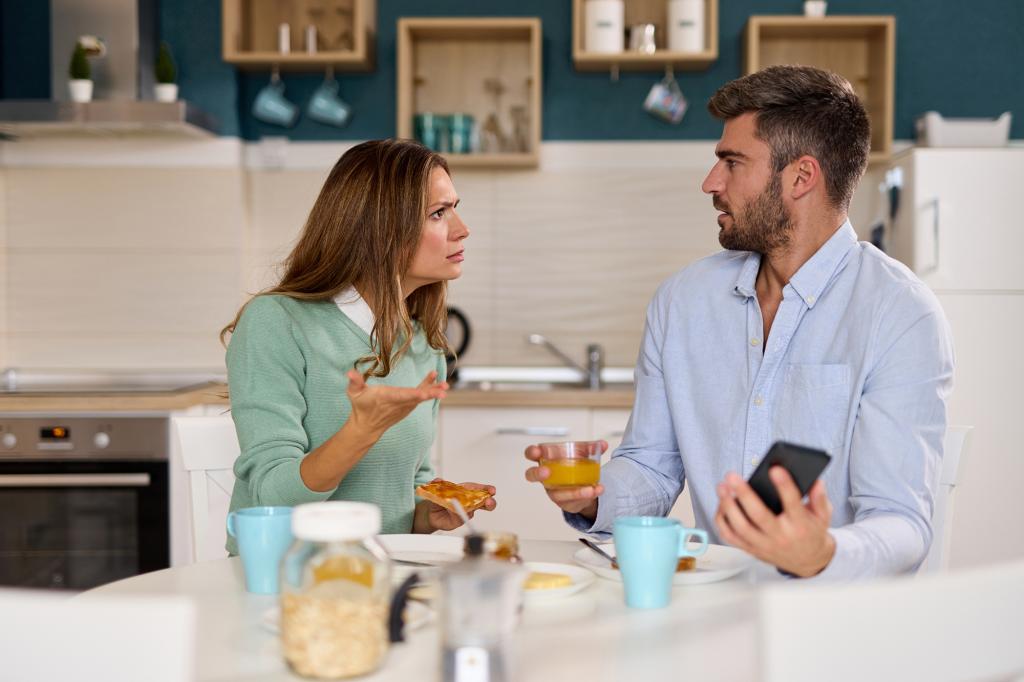 A stock image shot of a husband on his phone while his angry wife complains to him. 