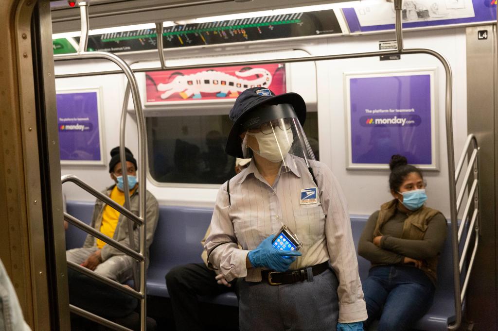 A USPS postal worker essential worker wearing PPE taking a 4-train from at Grand Central 42nd Street Station in the MTA NYC Transit Subway amid the COVID-19 coronavirus pandemic.