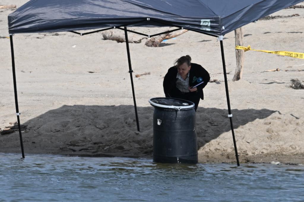 An official examining the barrel on the beach. 