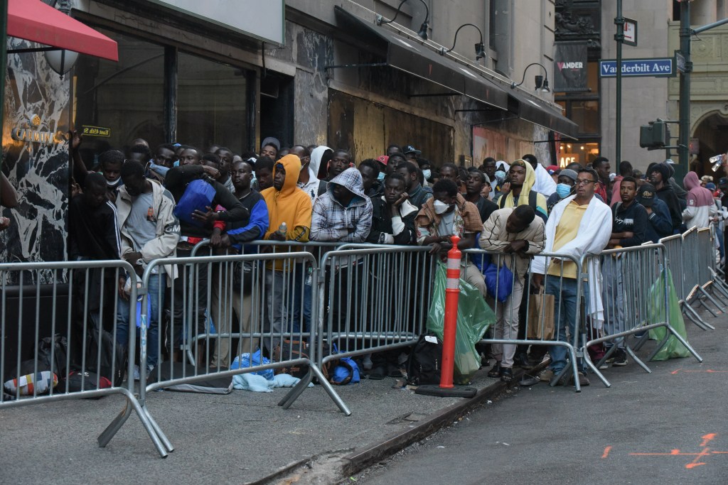 Migrants stand on line at the Roosevelt Hotel