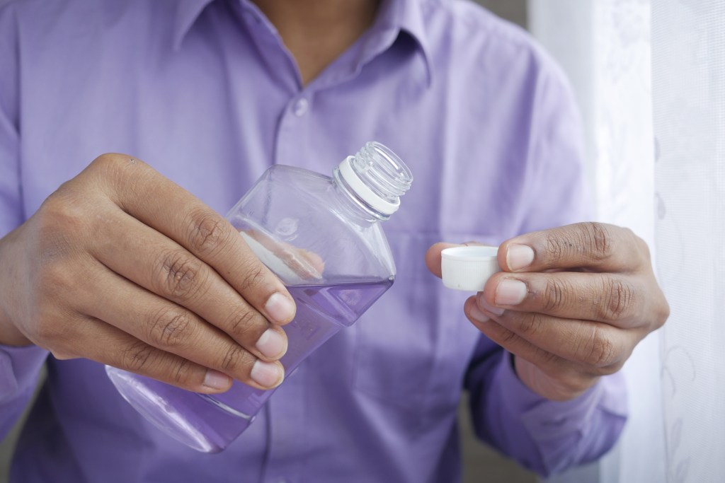 mouthwash liquid flowing into a cap , close up