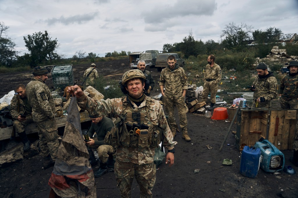 A Ukrainian soldier holds up the Russian flag.