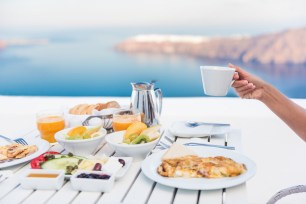 Morning person drinking coffee cup at breakfast table with mediterranean sea view.