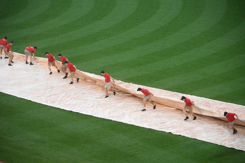 the grounds crew pulls the tarp onto the infield during the eighth inning in a game between the Boston Red Sox and Baltimore Orioles 