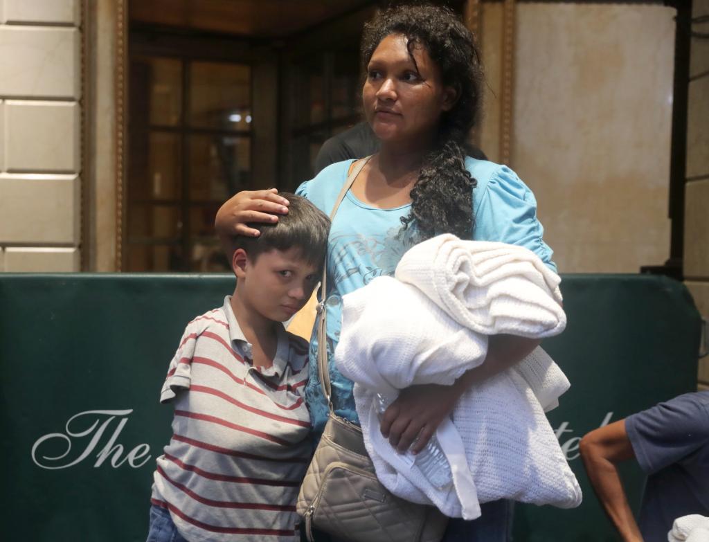 Migrant woman and her children wait in line outside the Roosevelt Hotel on Monday.