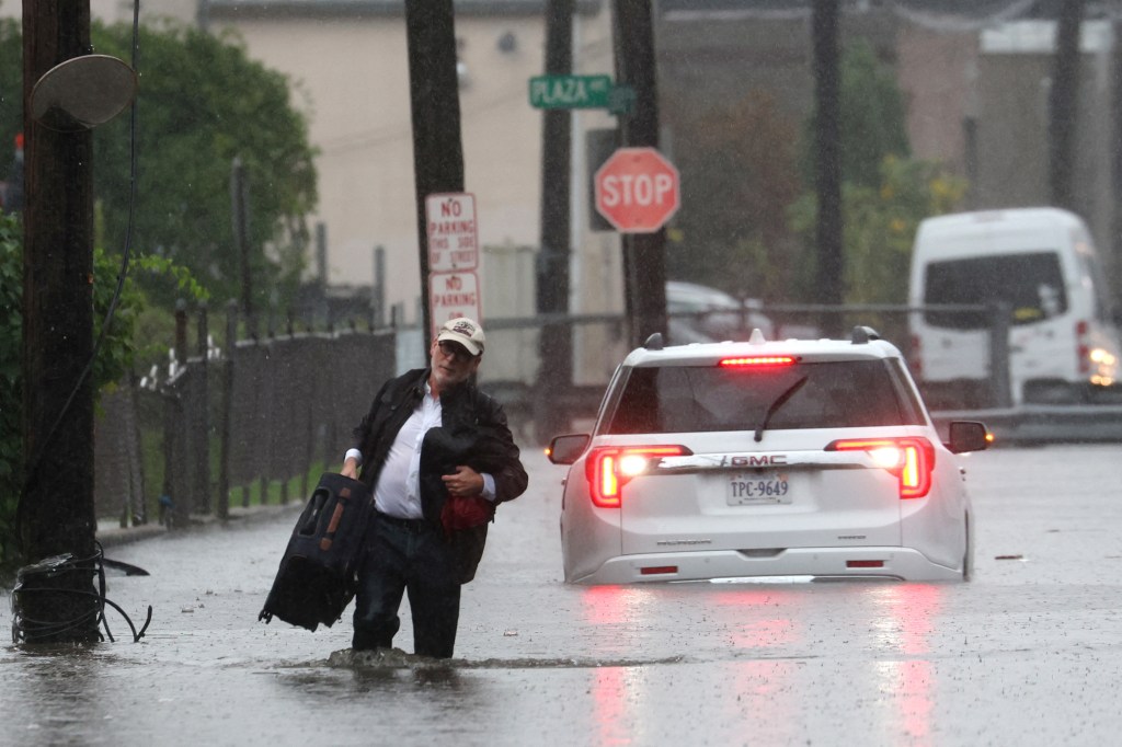 A man carries his belongings as he abandons his vehicle which stalled in floodwaters during a heavy rain storm in the New York City suburb of Mamaroneck in Westchester County, New York.