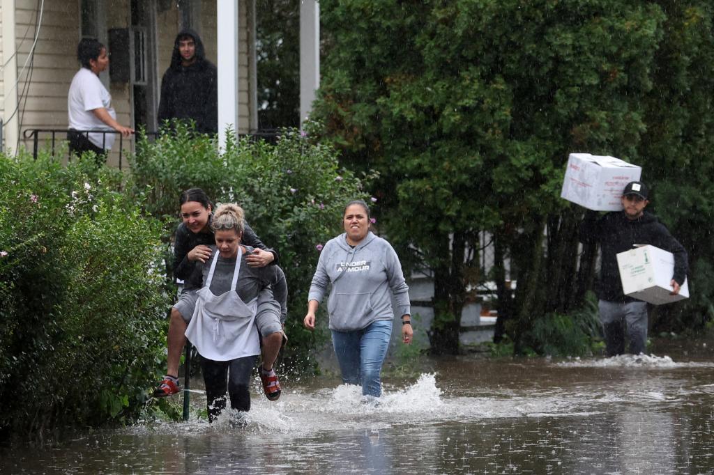 Residents walk through floodwaters during a heavy rain storm in the New York City suburb of Mamaroneck in Westchester County, New York.