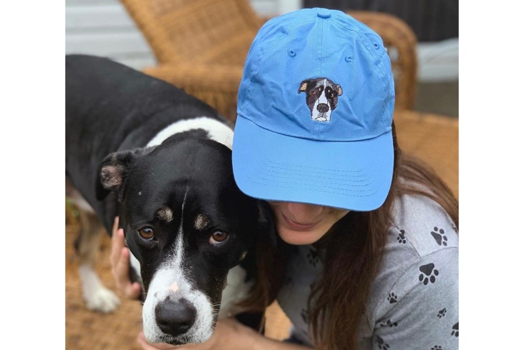 Woman and dog wearing hat with photo of dog on it