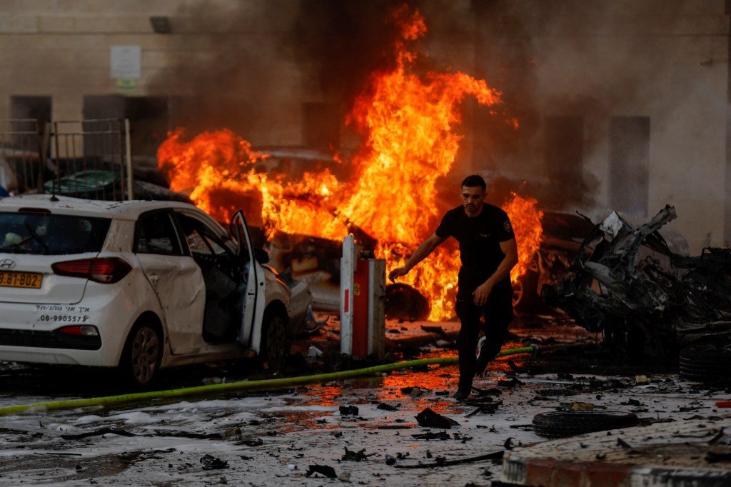 A man runs on a road as fire burns after rockets were launched from the Gaza Strip, in Ashkelon, Israel October 7, 2023. 