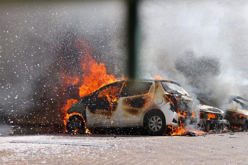 Cars are seen on fire following a rocket attack from the Gaza Strip in into southern Israel on October 7, 2023. 
