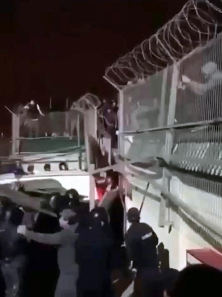 Law enforcement personnel prevent protesters from breaking info the fence of an airport in Makhachkala on Oct. 29, 2023.