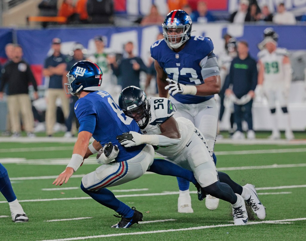 Daniel Jones is hit by Seattle Seahawks linebacker Derick Hall, as Evan Neal is behind him in the 4th quarter.