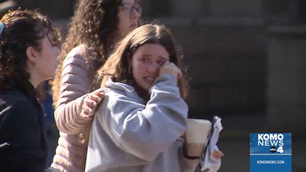 A female student is pictured crying as she was comforted by her friends.
