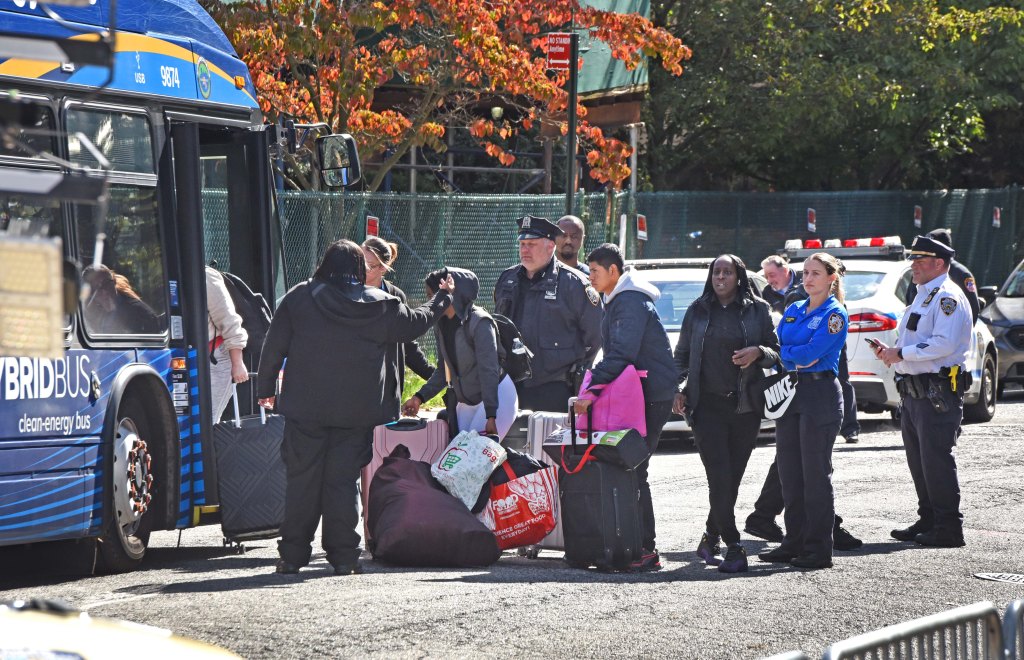 Migrants are seen boarding a bus after the fire department said the building was not safe