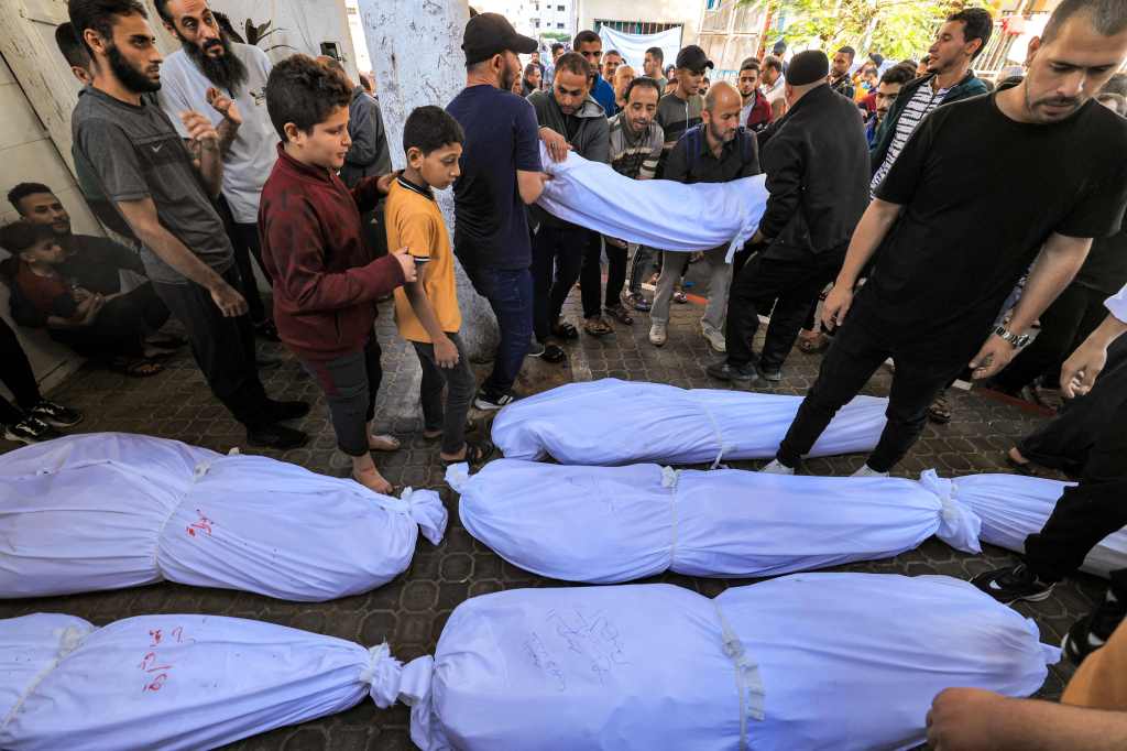 People gathered by the bodies of victims who died in the blast at Ahli Arab hospital in Gaza.