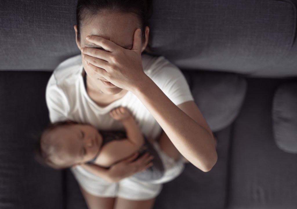 An overwhelmed mom holding her infant. 