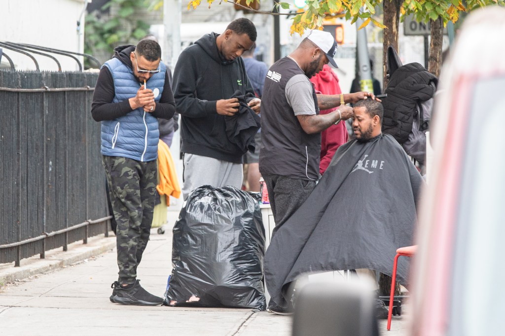 A barber giving haircuts in the migrant encampment.