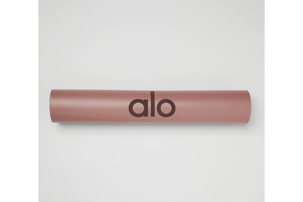 A rose gold alo yoga mat with the alo yoga logo printed on front.