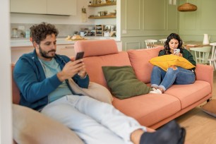 Young married couple using smart phone ignoring each other addicted to the internet and social network.