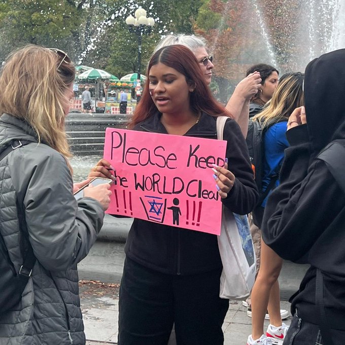 Woman with sign saying "please keep the world clean" and a picture of the star of david