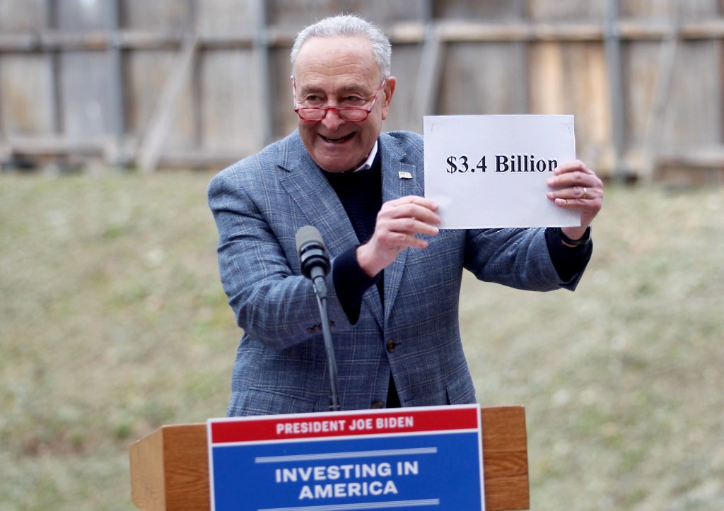 Chuck Schumer holding up $3.4 billion sign