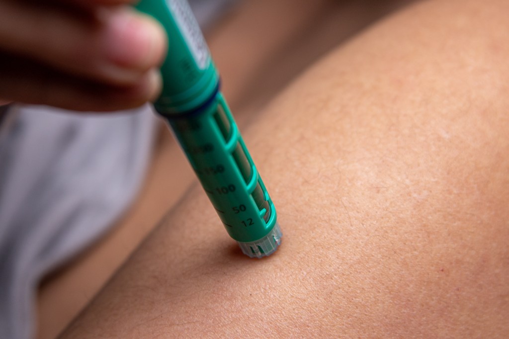 Woman inserting insulin pen into arm