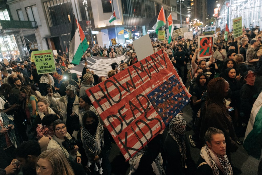 sign reading 'how many dead kids' at protest