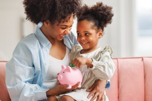 A mother and child save money in a piggy bank.