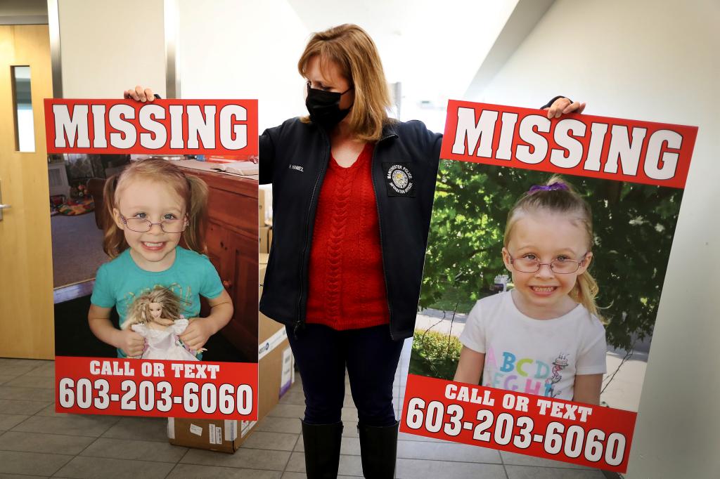 A photo of a NH police officer holding "missing" posters of Harmony Montgomery in both hands.