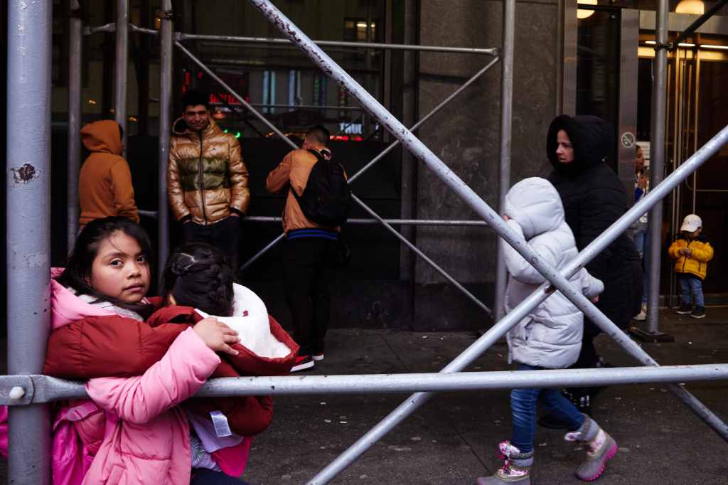 Migrants gather outside the Row NYC Hotel