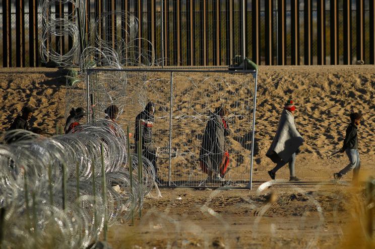 Migrants seeking asylum walk near the border wall, as they wait to be processed by U.S. Border Patrol in El Paso, Texas, during a day of low temperatures, as seen from Ciudad Juarez, Mexico December 29, 2023