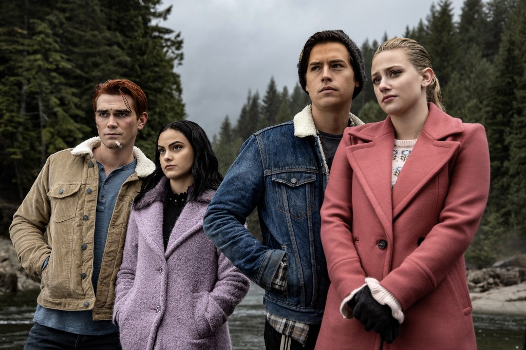 KJ Apa as Archie, Camila Mendes as Veronica, Cole Sprouse as Jughead and Lili Reinhart as Betty on "Riverdale" standing in a line, smiling. 