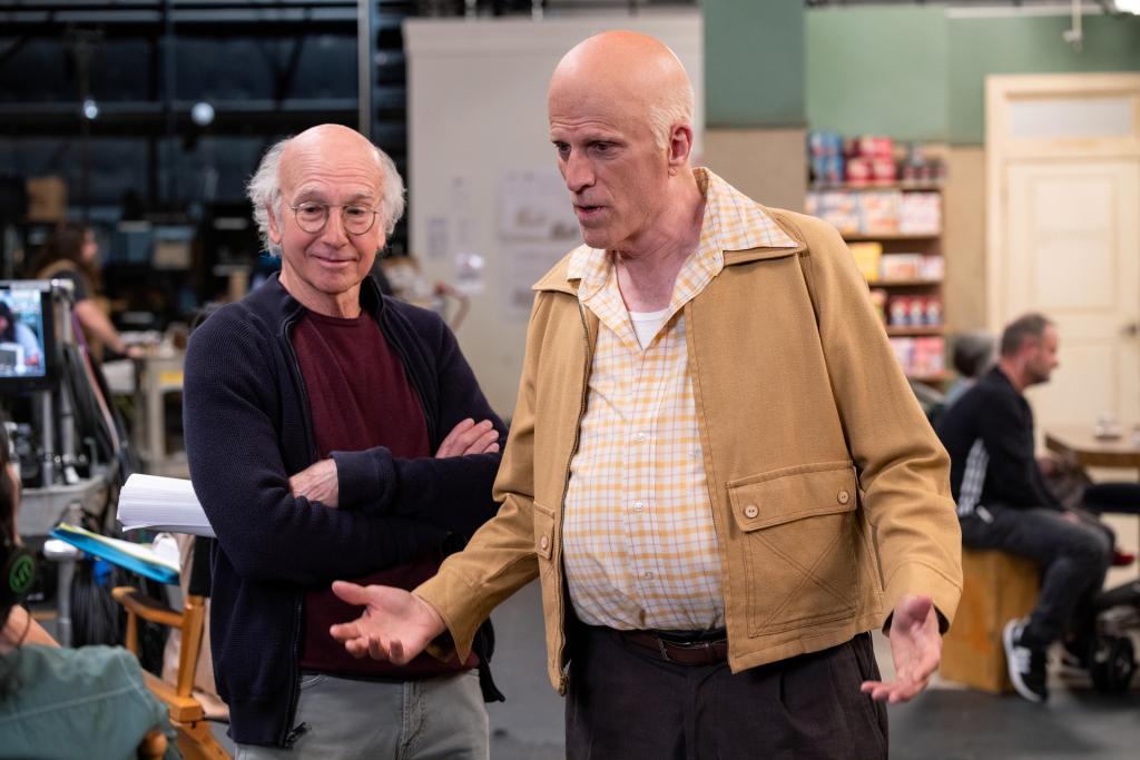 Ted Danson and Larry David in "Curb Your Enthusiasm." Danson is wearing a bald cap and has a big pot-belly. He's wearing a tan jacket and a yellow-and-white shirt that protrudes because of his gut.