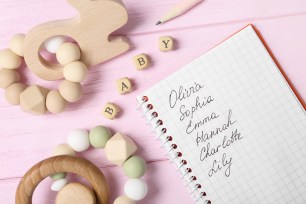 List of baby names and child's toys on pink wooden background, flat lay.