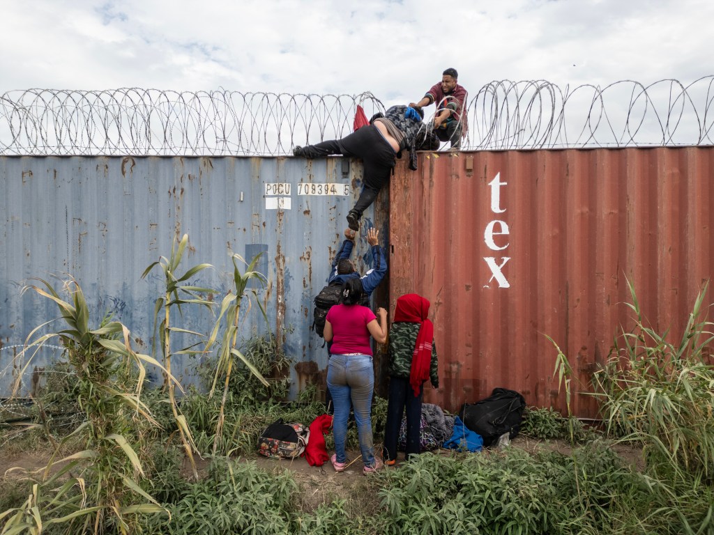 Migrants jump a border fence. 