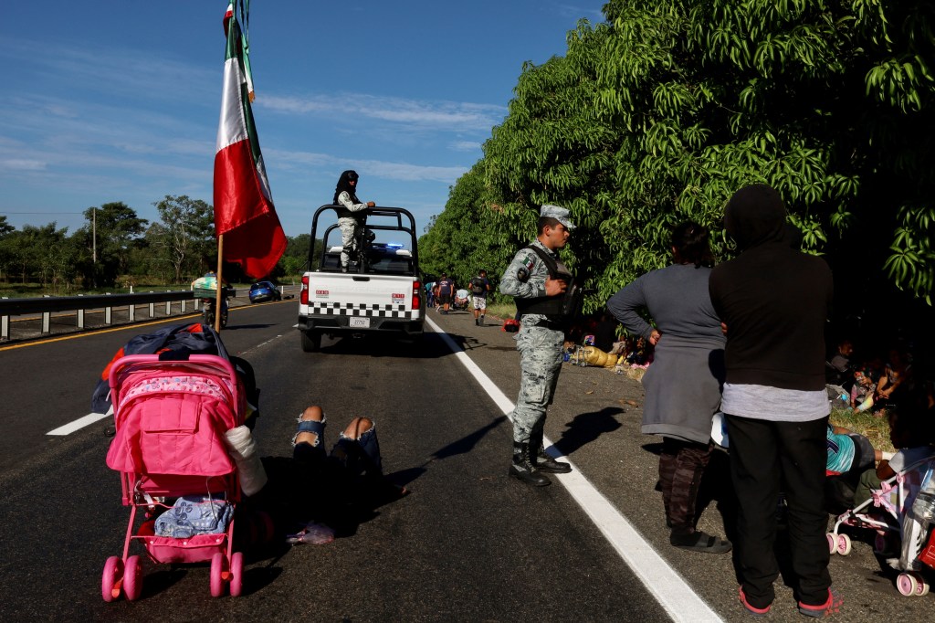 Migrants take a break on the side of the road before continuing walking in a caravan in an attempt to reach the U.S. border, in Escuintla, Mexico, December 28, 2023.