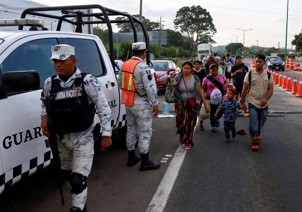 Migrants walk in a caravan next to members of the Mexican National Guard as they attempt to reach the U.S. border on Christmas day.