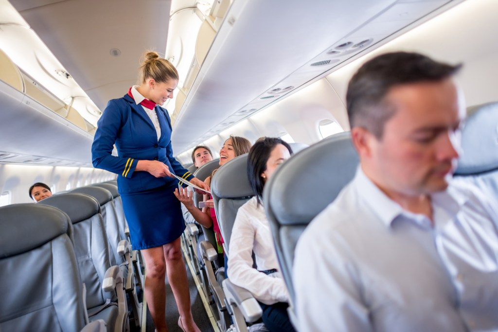 A flight attendant explaining the duty-free options.