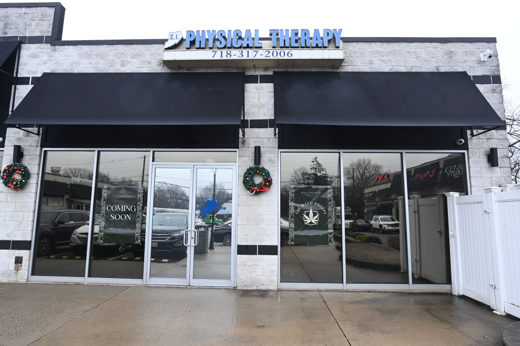 Commercial storefront with a sign for "SI Physical Therapy" that has paper signs announcing The Weed Shoppe dispensary is coming soon.