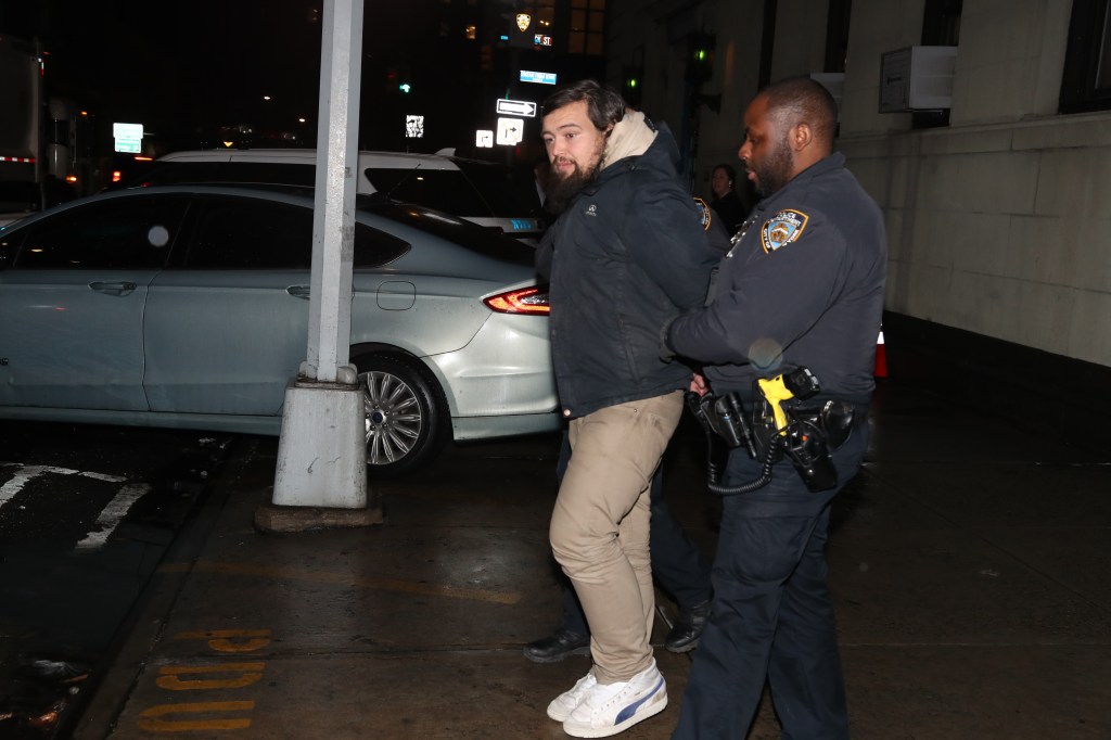 A man is escorted by a police officer outside of the 1st Precinct - Taylor Swift stalker David Crowe was arrested.