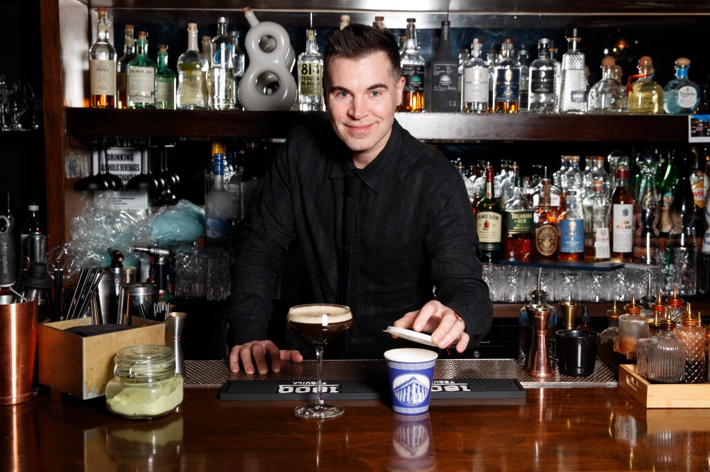 Richard Wheeler wearing all black with a Greek deli to-go cup and an espresso martini.