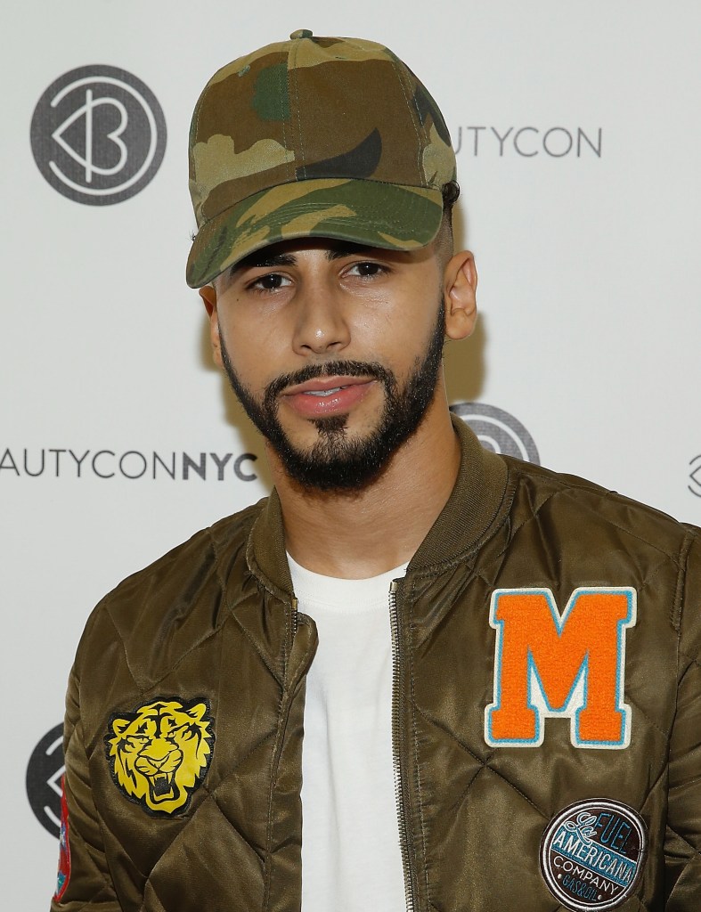 Adam Saleh red carpet photo in camo hat, green varsity jacket