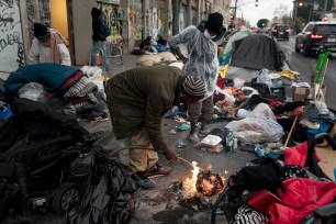 Robert Mason, a 56-year-old homeless man, warms up a piece of doughnut over a bonfire he set to keep himself warm on Skid Row in Los Angeles